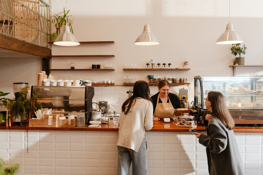 A female cafe worker engages in lighthearted conversation with visitors, taking their orders with a smile. A concept of simplicity, customer orientation, and the essence of working life.