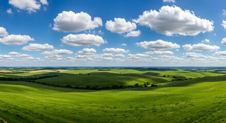 Obraz premium Rolling green hills under a blue sky with fluffy clouds, rural countryside scenery, bright daylight