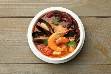 Delicious seafood soup in bowl on wooden table, top view