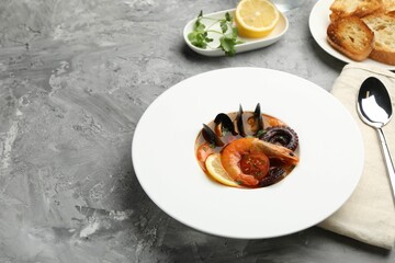 Delicious seafood soup served on gray textured table. Space for text
