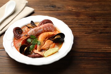 Delicious seafood soup in bowl on wooden table, closeup. Space for text