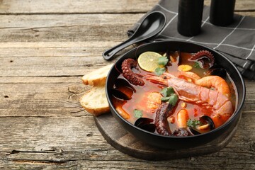 Delicious seafood soup served on wooden table, closeup. Space for text