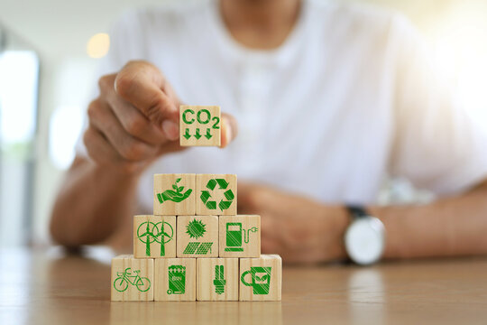 Greenhouse gas and carbon dioxide emission reduction concept with man hand in white shirt holding related factors icons screen on wooden dice