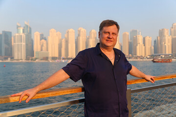 Blond man on Dubai promenade in the rays of the setting sun.
