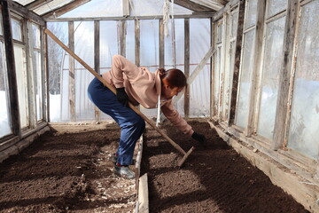 woman in a greenhouse working with a spade. 