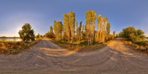 Spherical panorama of late summer evening on dirt road near pond surrounded with green bushes and trees