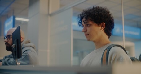 Diverse Passengers at Airport Check-in Counter: Young Man Verifying Personal ID Data by Facial...