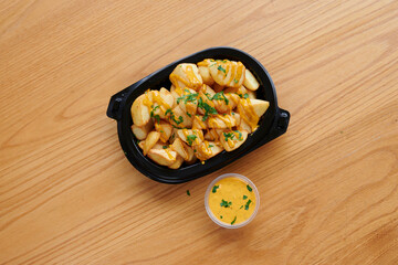 A tray of food with a sauce on it. The sauce is yellow and is in a plastic container