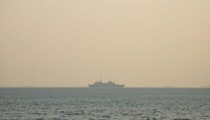 Fototapeta premium Ship Sailing Across Calm Waters With Hazy Skyline in the Distance During Golden Hour
