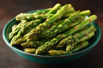Freshly harvested asparagus displayed in a turquoise bowl, ready for cooking or serving at a dining table