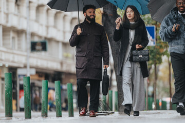 A group of business professionals is seen walking in the street, holding umbrellas on a rainy day....