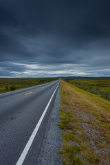 Epic cloudy landscape of an empty highway through the tundra of  Norway