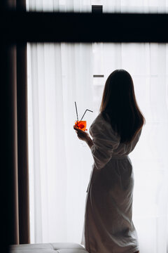 Relaxing Woman in Robe Enjoying Drink by the Window