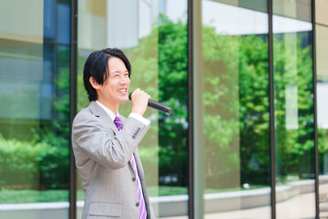 Fototapeta premium マイクを使って街なかで演説をするスーツを着た男性