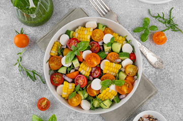 Sweet corn salad with arugula, tomatoes, cucumber, red onion and mozzarella. Healthy food. Top view.