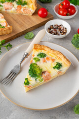 Homemade tart or quiche with salmon, broccoli, cheese and cream filling on a gray stone background. Healthy food. Selective focus.