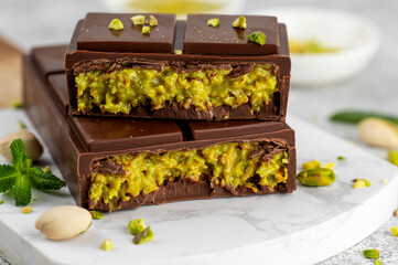 Dubai chocolate with kadayif dough and pistachio paste. Trend dessert on a board on a concrete background. Copy space.