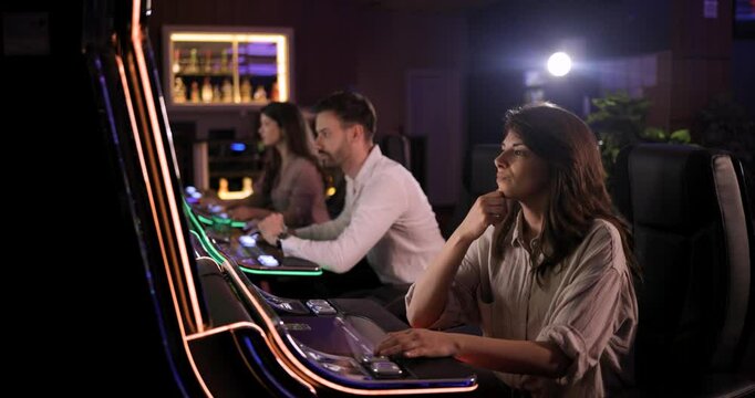 Woman Tries Her Luck at Slot Machine in Casino with Friends