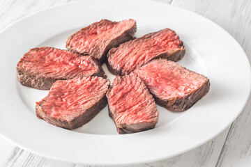 Perfectly sliced medium-rare fillet mignon steak served on a white plate