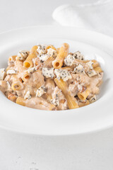 Penne pasta served with creamy walnut blue cheese sauce on white plate