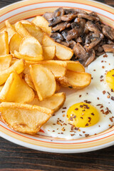 Golden potato dippers, fried eggs, and mushrooms on rustic textured table setting