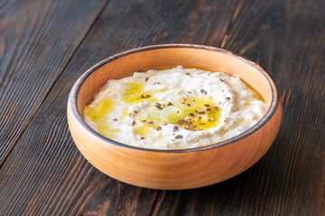 Creamy baba ghanoush in wooden bowl with chili and olive oil