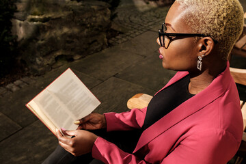 Obraz premium Young businesswoman reading a book outdoors