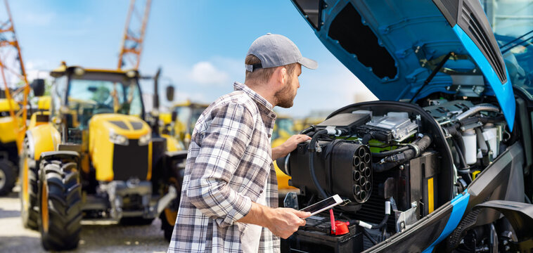 Man using digital tablet to inspect tractor engine with modern modern technology