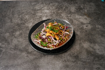 A plate of food with a clear bowl on top of it. The bowl is filled with onions and meat