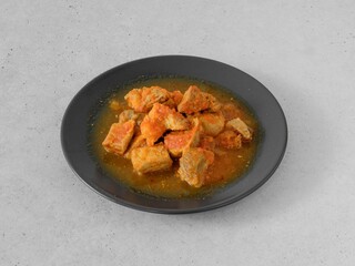 A plate of meat with sauce on it. The meat is cut into small pieces. The sauce is orange