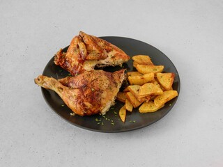A plate of chicken and potatoes. The chicken is cut in half and the potatoes are cut into cubes