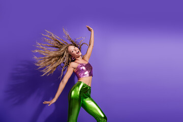 Vibrant young woman dances joyfully in glittering fashion against a bold purple background