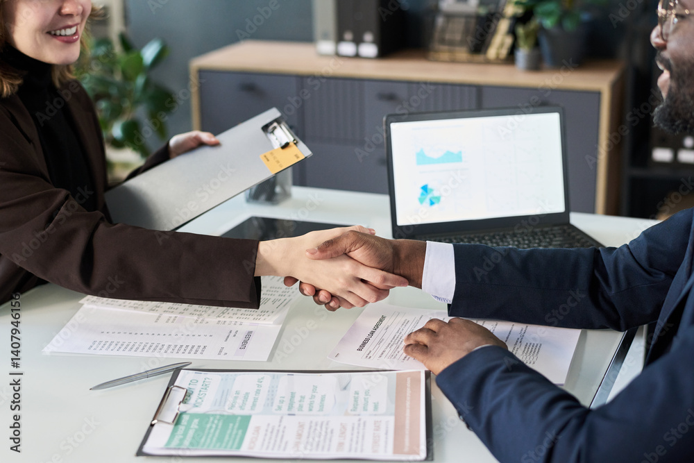 Poster close-up of business colleagues shaking hands while sitting at table at meeting in office