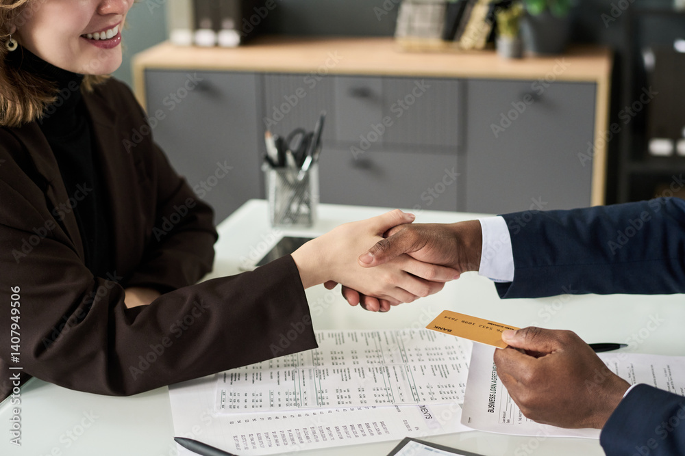 Poster close-up of woman shaking hands with manager while getting credit card from him at meeting