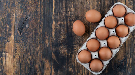 Fresh brown eggs in carton on rustic wooden table