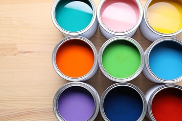 Cans of bright paints on wooden table, flat lay. Space for text