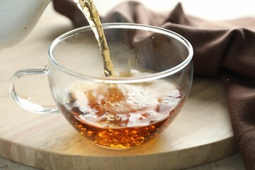 Pouring aromatic tea into cup at table, closeup