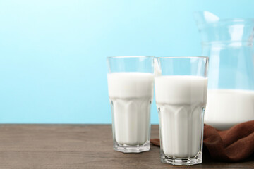Fresh milk on wooden table against light blue background. Space for text