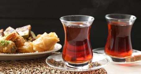 Traditional Turkish tea in glass cups and sweets on white table, closeup