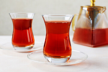 Traditional Turkish tea in glass cups and teapot on white table, closeup