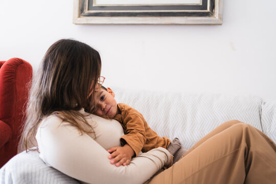 Mother and son are cuddling on the couch, enjoying a quiet moment of affection and bonding