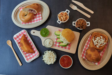A table with a variety of food items including sandwiches, burritos, and other dishes. There are also utensils such as forks and spoons