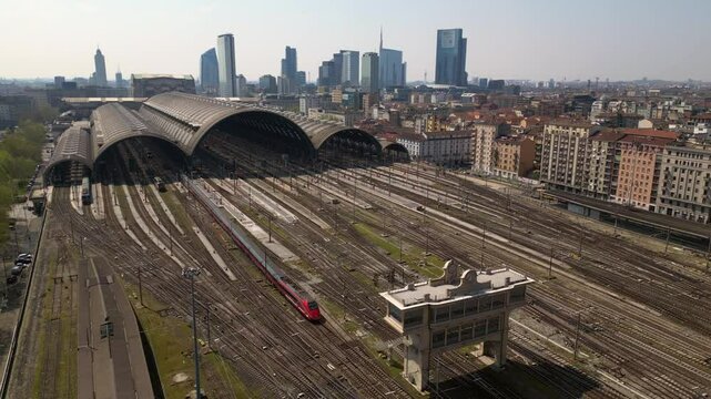 Europe,Italy, Milan 04,27,2025 drone view of Centrale train station railway with skyline in downtown - travel with Frecciarossa and Italo high speed trains to Bologna, Florence, Rome and Naples 