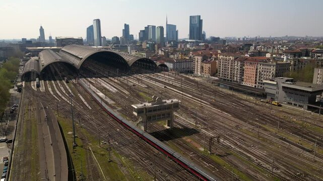 Europe,Italy, Milan 04,27,2025 drone view of Centrale train station railway with skyline in downtown - travel with Frecciarossa and Italo high speed trains to Bologna, Florence, Rome and Naples 