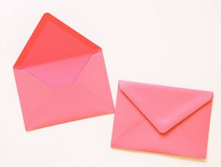 two pink envelopes on a plain white background. The envelope on the left is open, displaying its triangular flap, while the one on the right is closed, showing a neat, pointed flap (1)