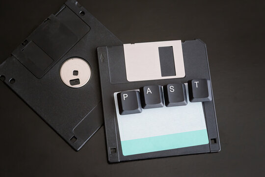 Old computer floppy disks with the word "past" made from computer keyboard keys, on a dark background, close-up shot, outdated technology from the 20th century, an old data archive

