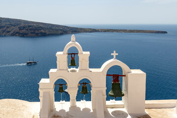 Bell tower of a white chapel and view at the sea and Santorini island in Greece, Europe