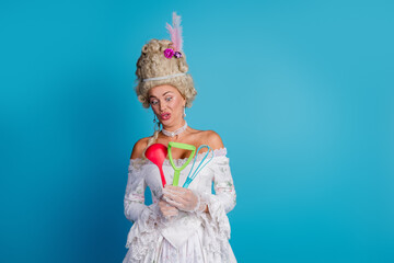 Fototapeta premium Charming woman in a styled baroque costume holding modern kitchen utensils, blending historical fashion with contemporary objects