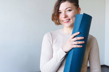 Beautiful girl getting ready for yoga indoors in daylight.