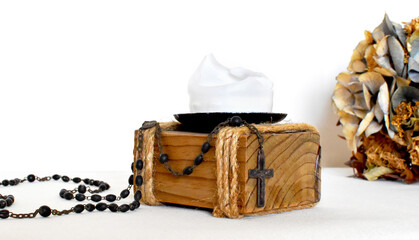 Dark rosary for prayers on a light background, yellow dried flower and wooden candlestick with white candle